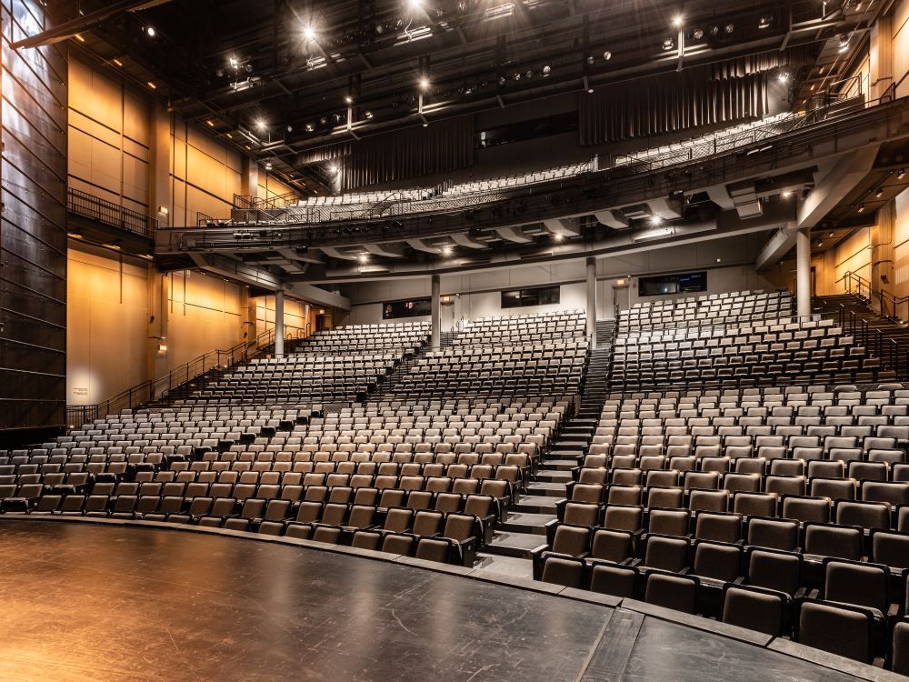 Image of an empty auditorium. The shot is from the stage looking towards the seating. 