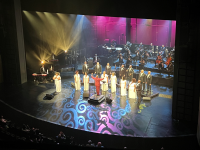 Image of the stage from the balcony. On stage an orchestra and a choir perform.