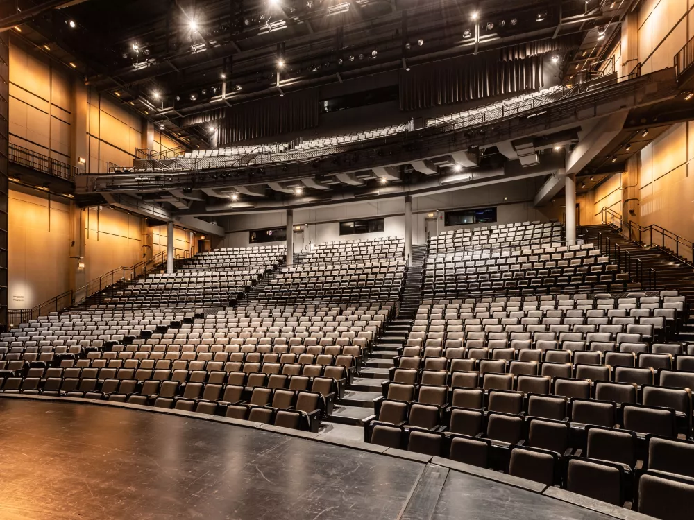 Image of an empty auditorium. The shot is from the stage looking towards the seating. 