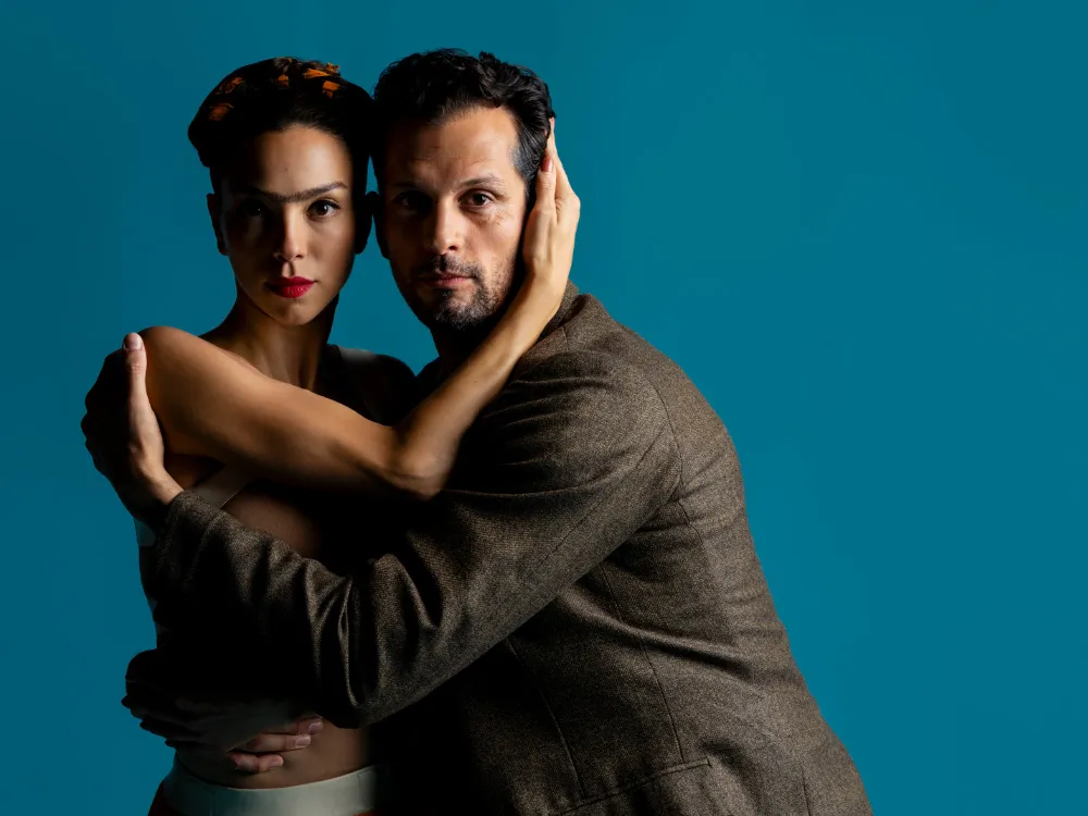 A woman that resembles Frida Kahlo hugs a man. 