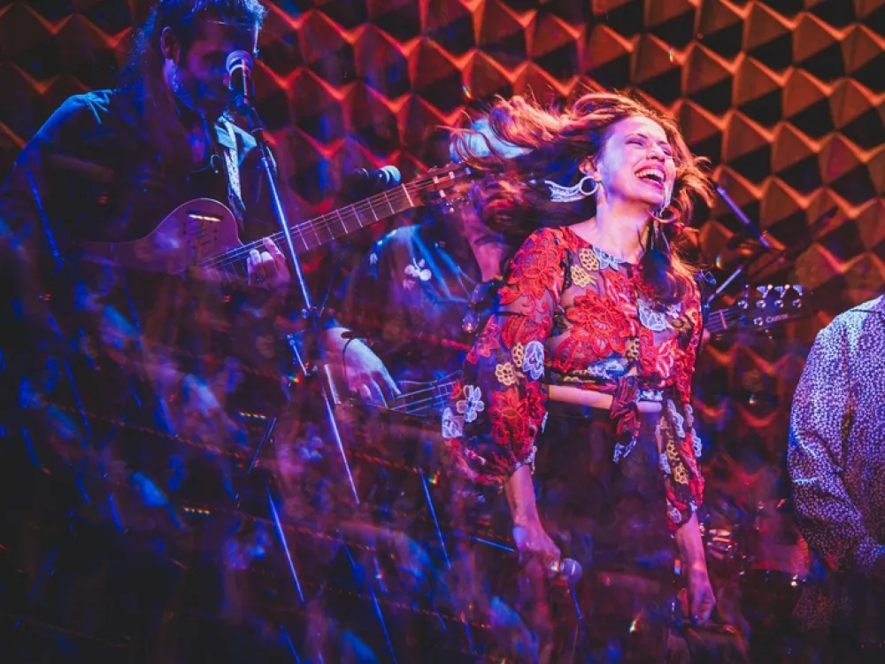Sandra Delgado smiling and singling with a band. 