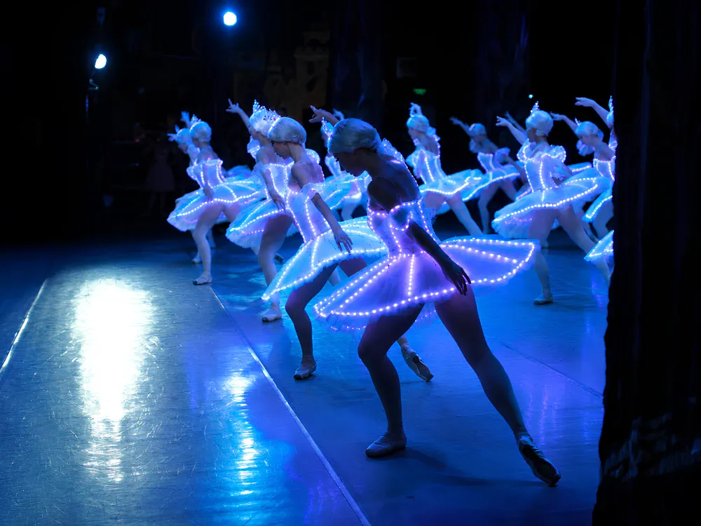 Ballerinas with their costumes lit up with small lights.