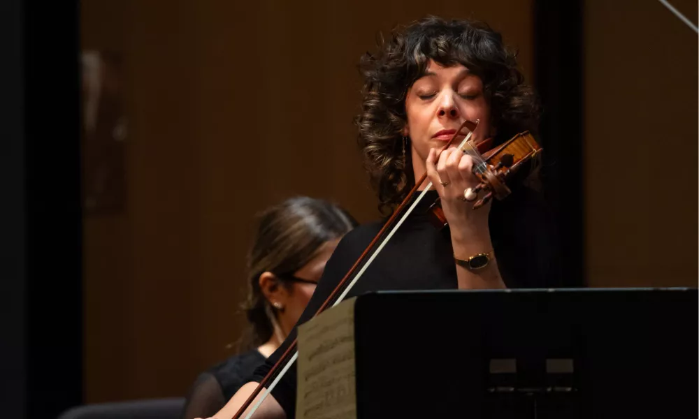 Photo of Gina DiBello playing the violin with her eyes closed