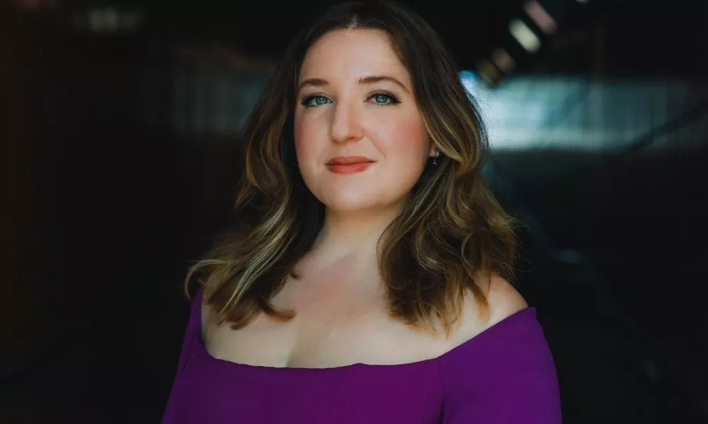 Headshot of Hannah De Priest. A woman in a purple shirt.