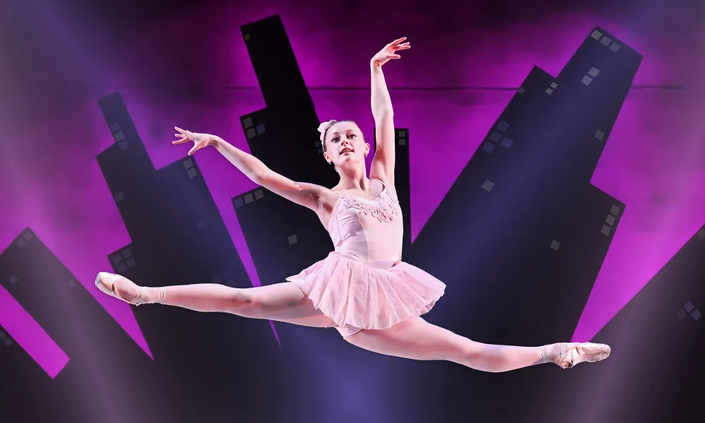 Ballet dancer in a pink costume performs a split leap midair against a purple city skyline backdrop.