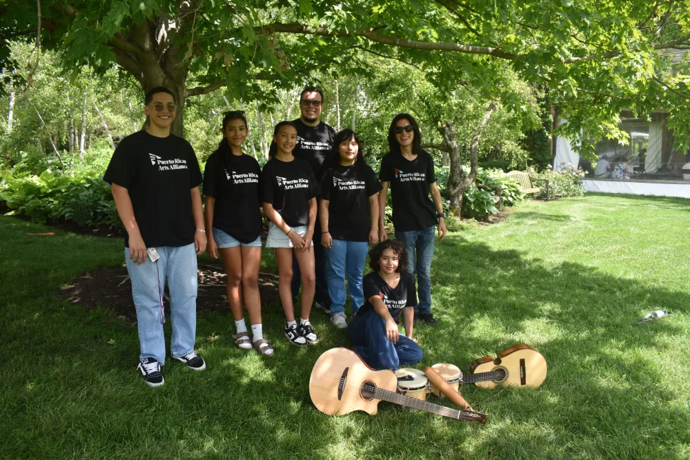 The Latin Music Project Ensemble stand together in a park.