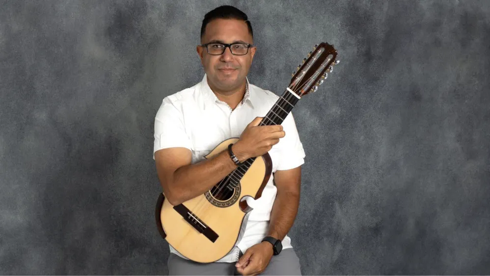 A man holding a Cuatro guitar.