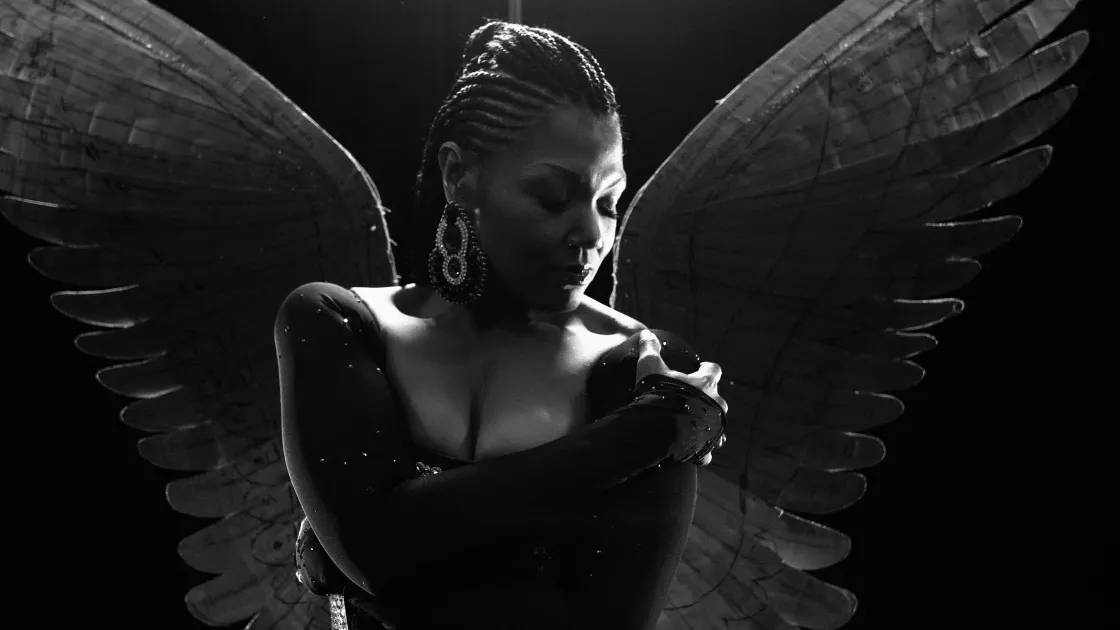 Soprano Measha Brueggergosman with her arms crossed across her chest with wings behind her