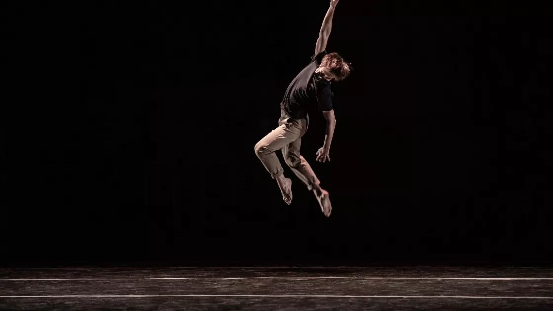 dancer leaps upward with one hand in the air