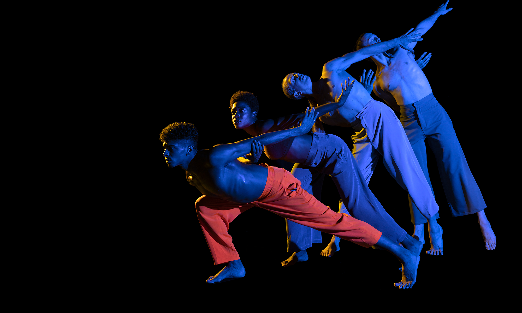 Four dancers leaning forward in a line