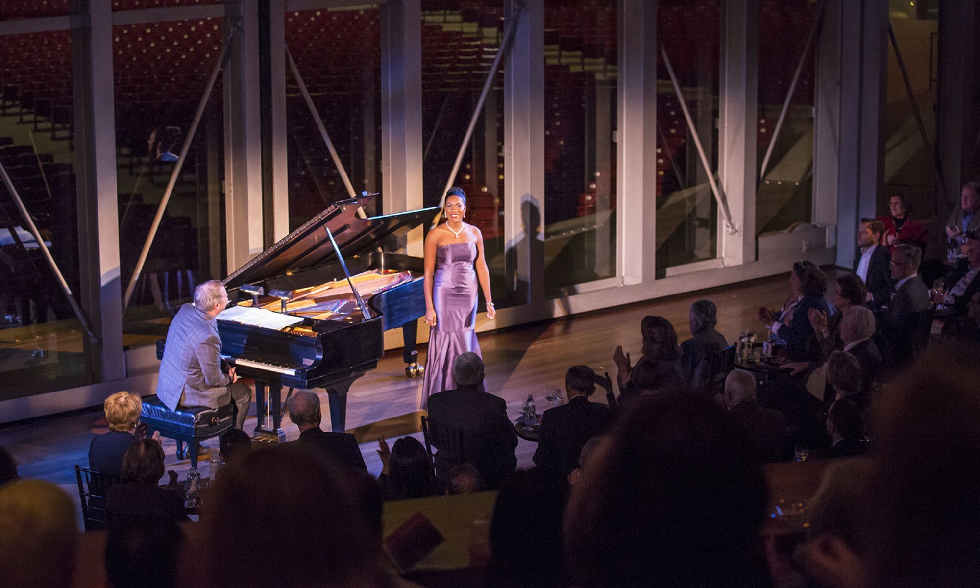J'Nai Bridges in a purple dress smiling next to Craig Terry sitting at piano