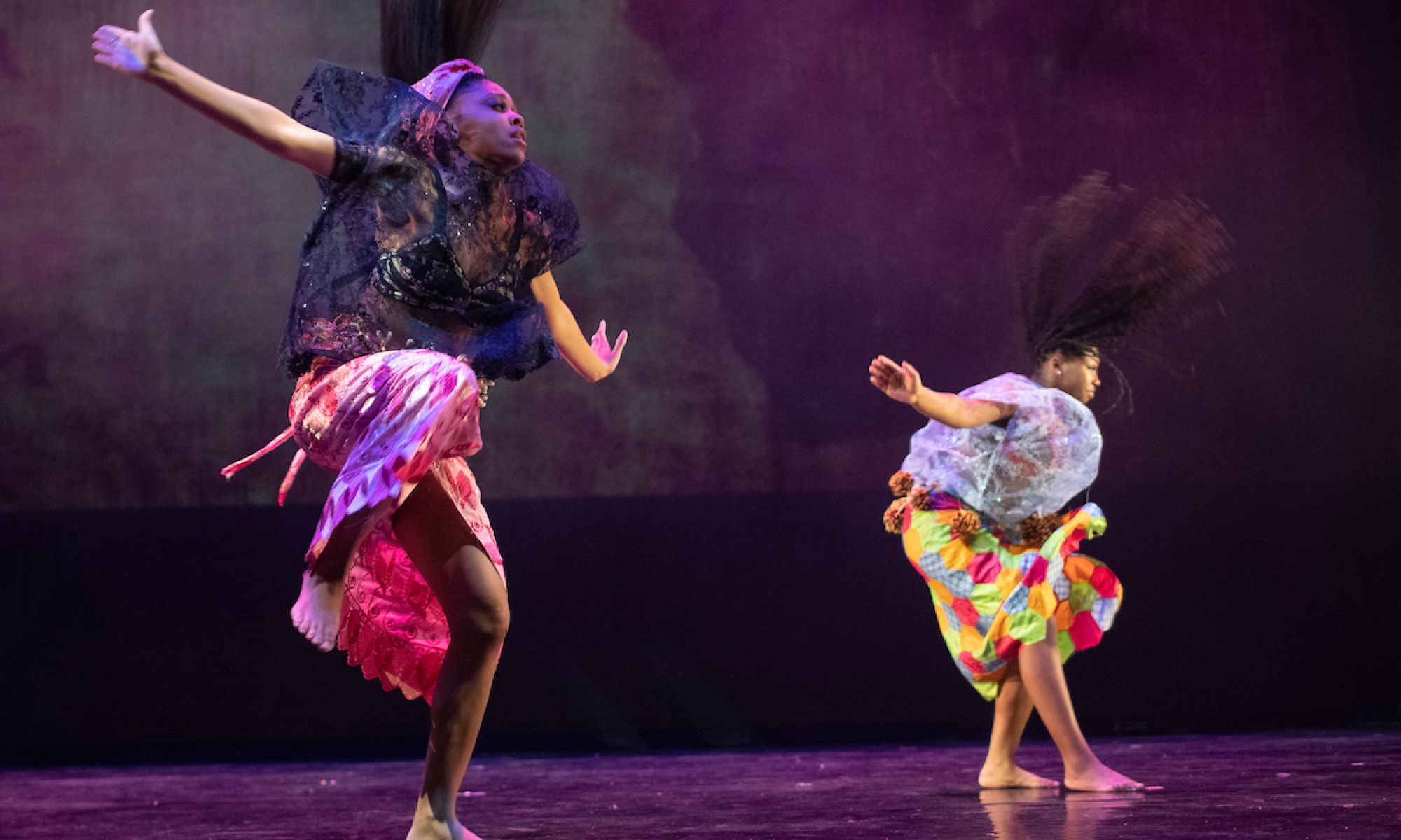 Two African American female dancers in motion. Arms spread apart hair  flowing. The dancers 