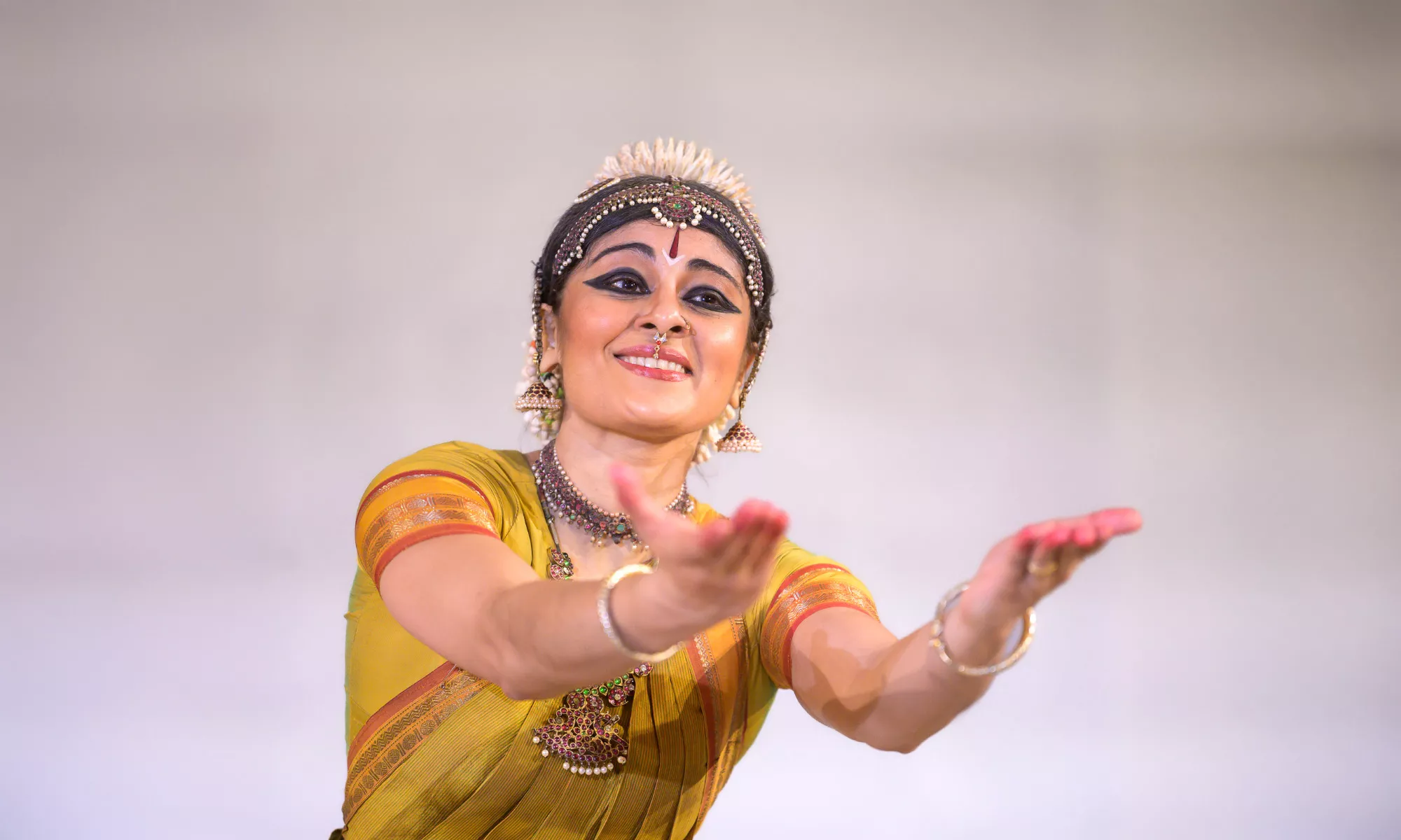 A woman in Hindu attire extends her arms out. 