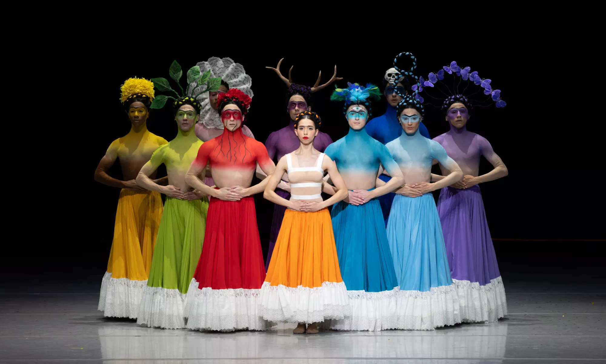Dancers standing, wearing colorful costumes.