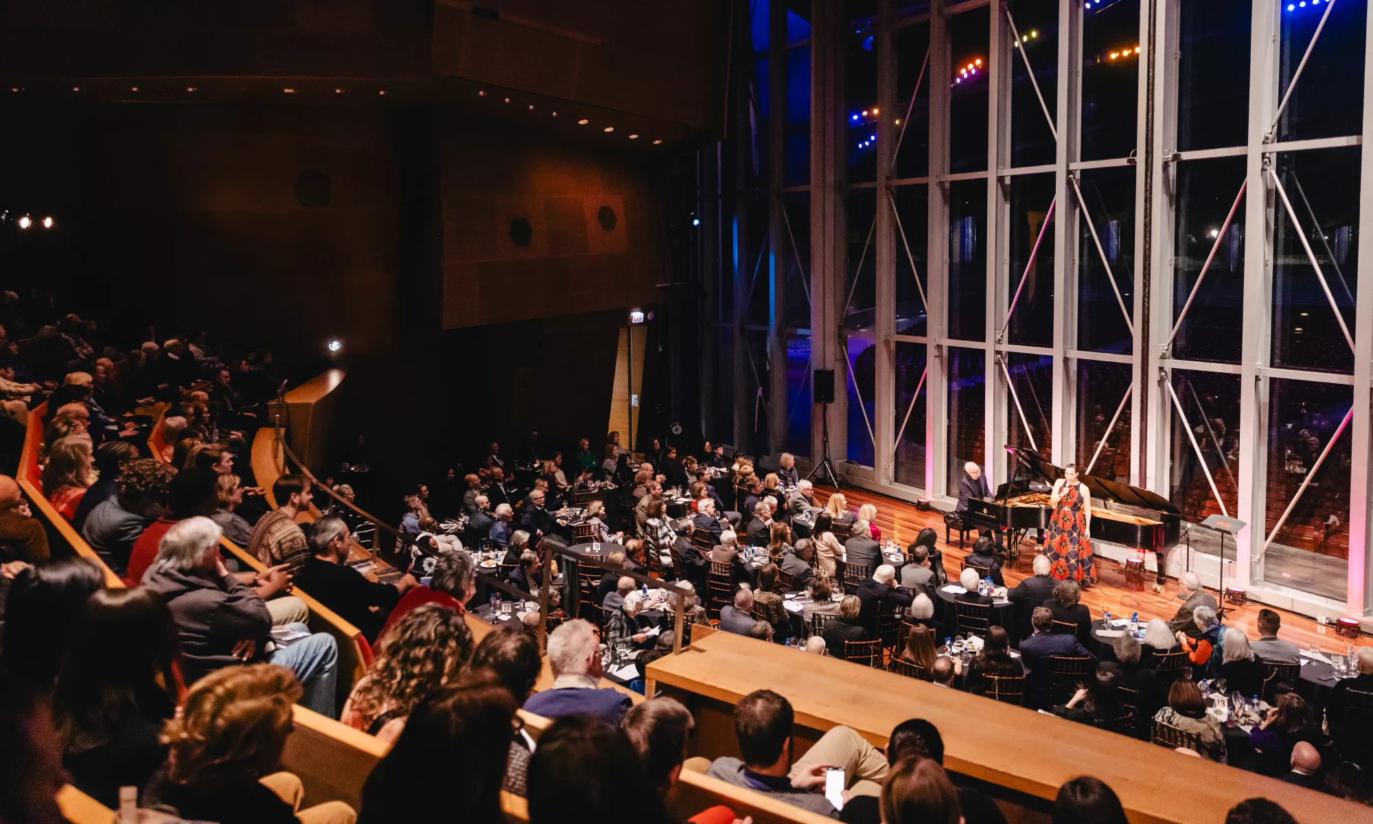 An audience watching a performance on the Pritzker stage and Millennium Park as the background.