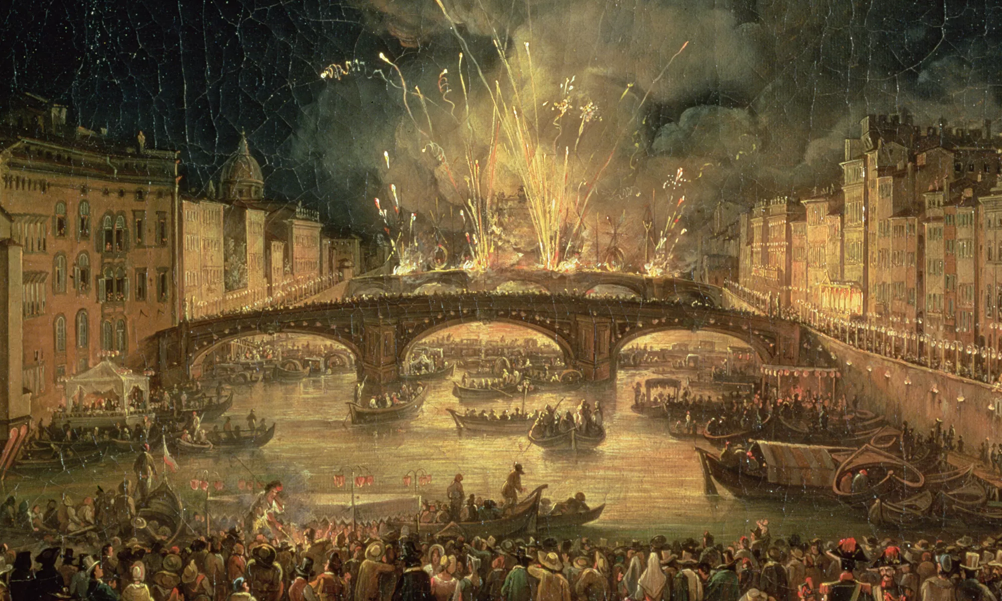 Image of fireworks over a bridge with boats on the river and a crowd