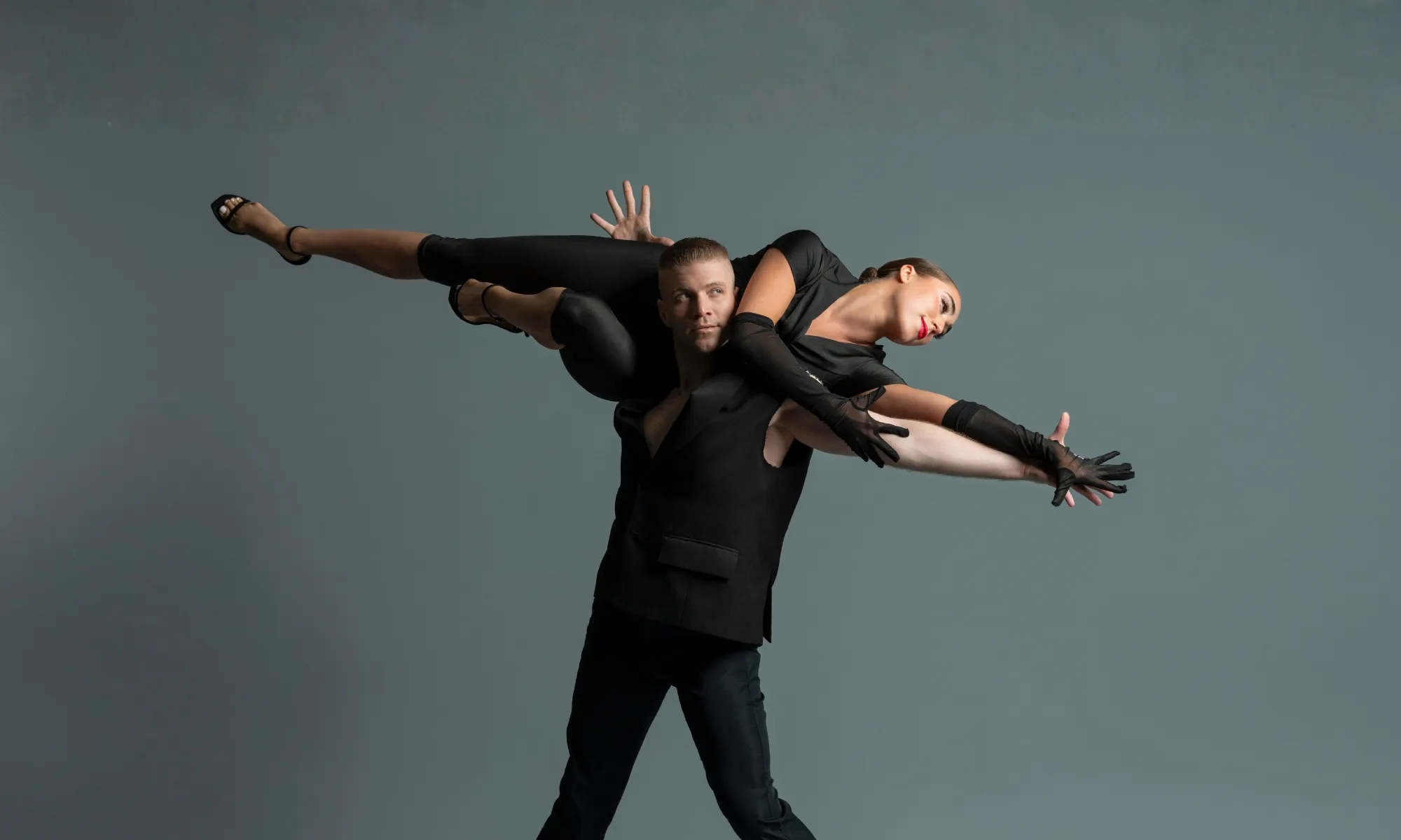 A male dance carries another dancer over his shoulders. The other dance extends horizontally.