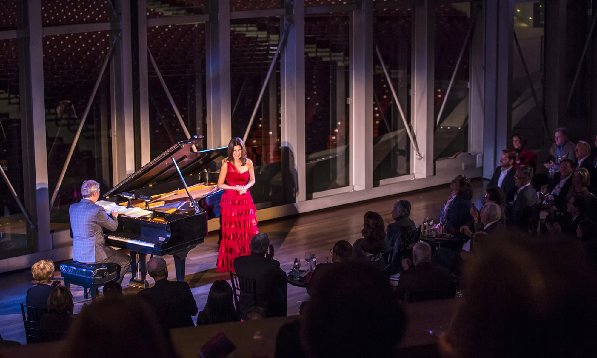 A pianist and singer on the Pritzker stage in front of an audience.
