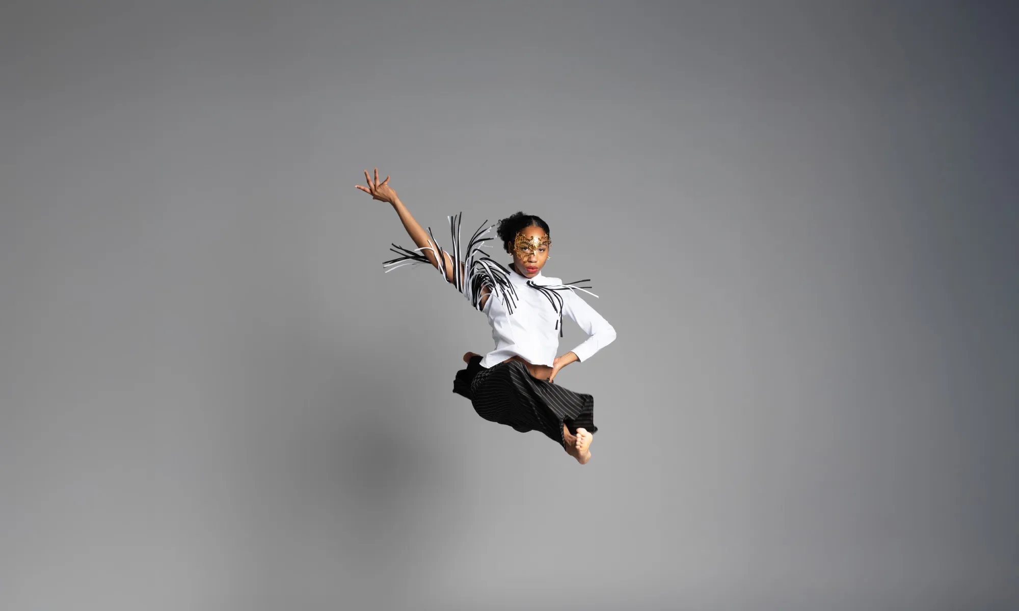A dancer doing a split in the air and raising her arm up.