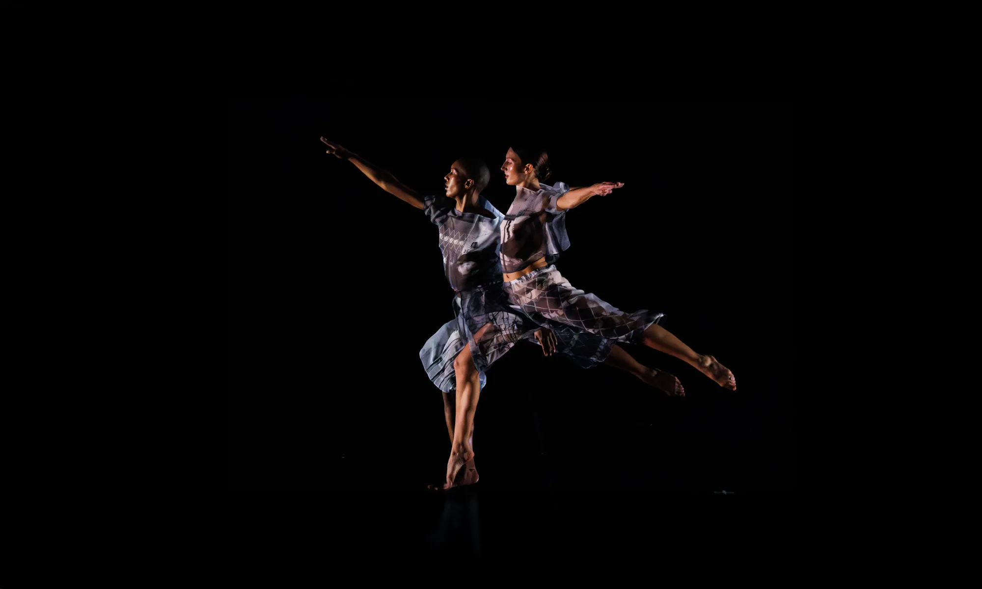 Two dancers jumping into the air.