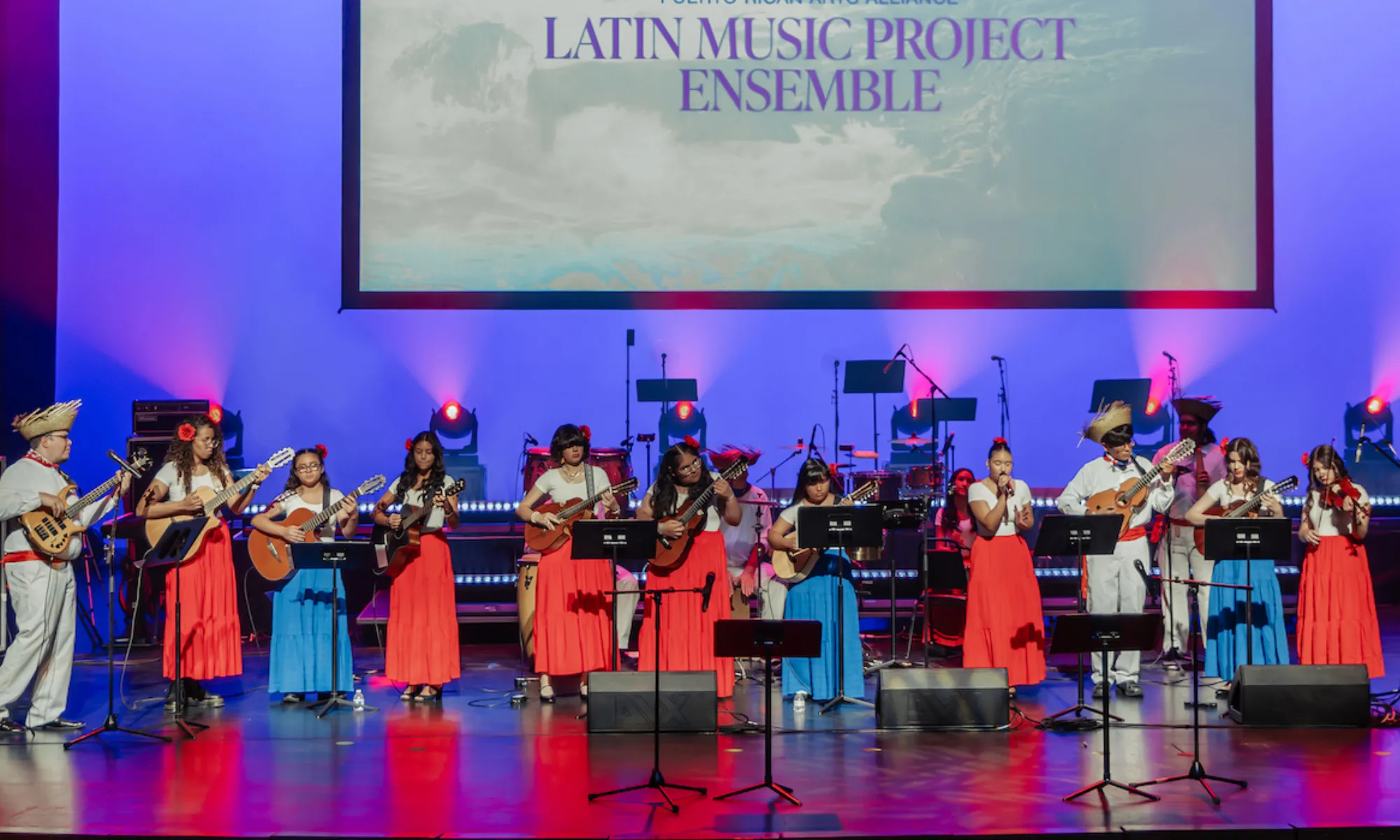 An ensemble of young musicians playing on the Harris stage. They all play the Cuatro guitar.
