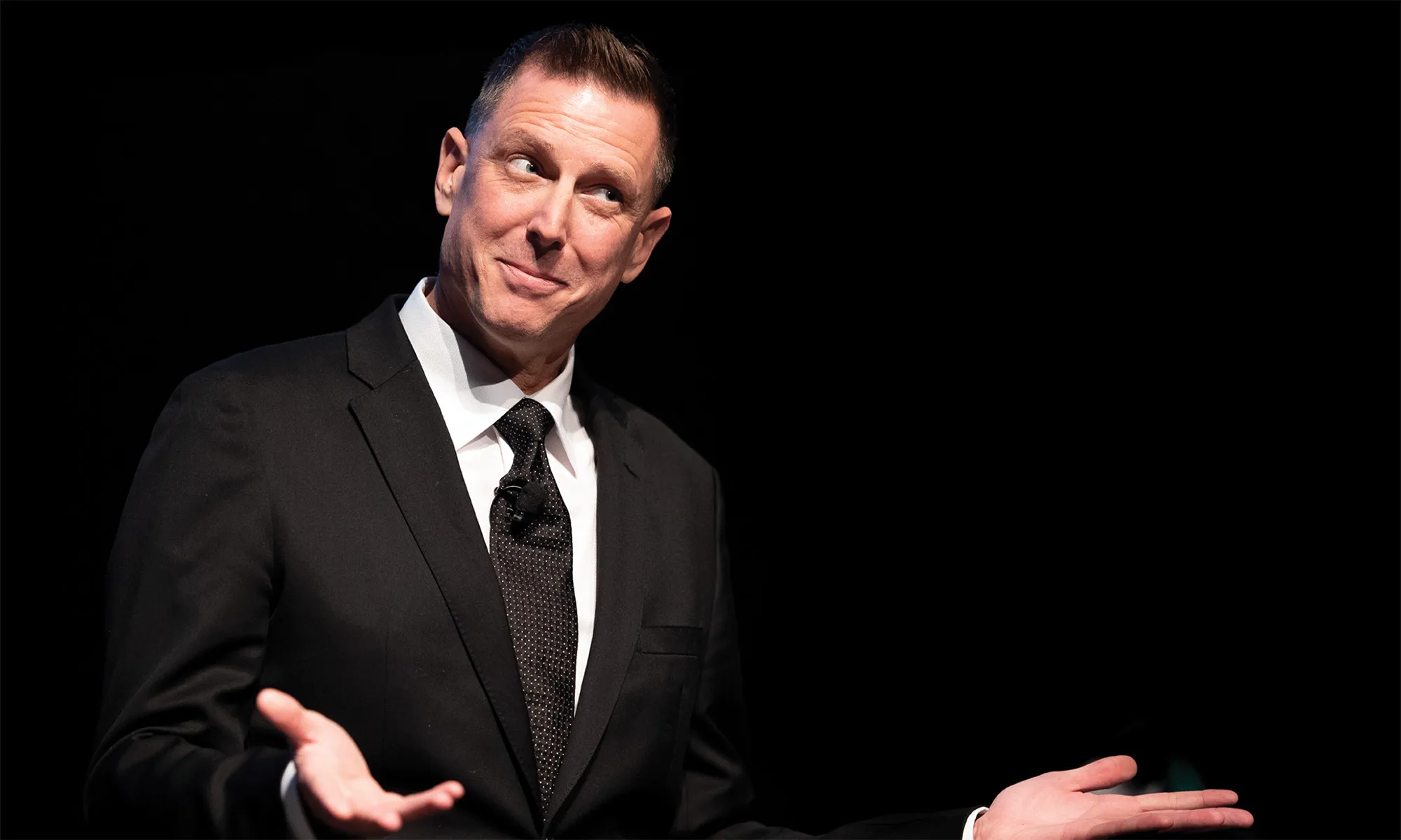 A man in a suit shrugging.