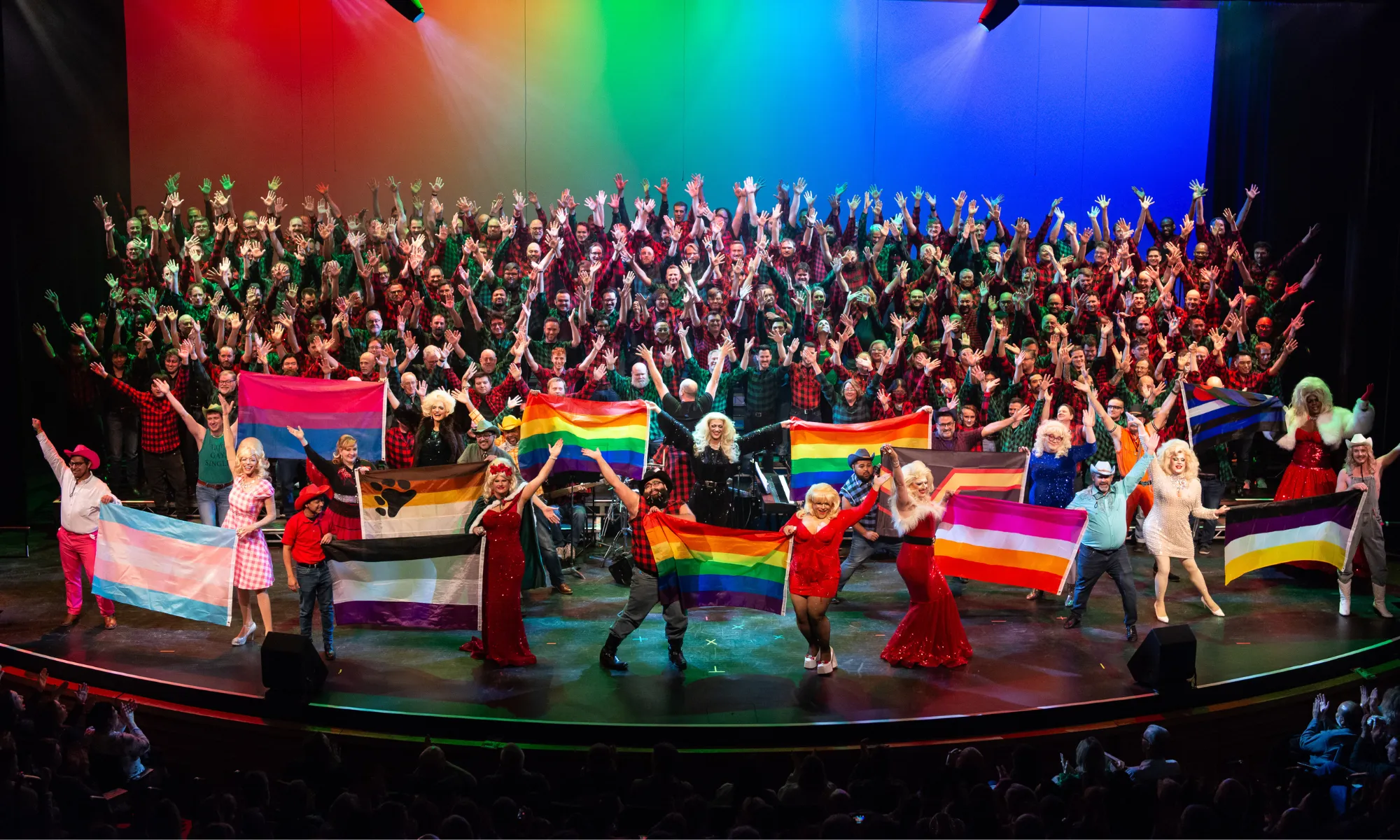 A large chorus holding LGBTQIA+ flags