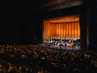 Image of a full auditorium watching an orchestra on stage