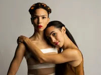A woman that resembles Frida Kahlo is hugged by another woman.