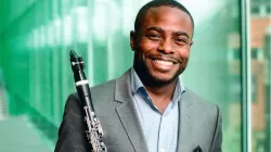Head shot of artist Anthony McGill, holding his flute and smiling