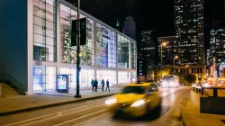 The street in front of the Harris Theater facade with a taxi rushing by