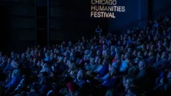 Audience inside the Harris Theater auditorium with Chicago Humanities Festival projected on the walll