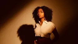 Samara Joy with her hands in her pockets and a shadow behind her