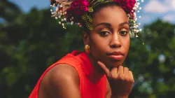Jazzmeia Horn wears a bright orange top with a flower crown on her head