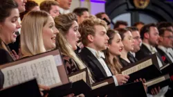 A close up of several singers holding their music folder with their sheet music.