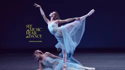 Two dancers on stage with baby blue dresses. One is lying on the floor while the other is in an arabesque position. A third dancer is hidden in the back.