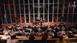 Image of an audience watching an opera singer on the Pritzker Pavilion stage amongst the night view of the Chicago skyline.