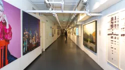 The Guthman Gallery hallway. Frames and murals are hung on the wall on the left and right walls.