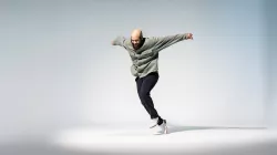 A tap dancer about to step. His arms are outstretched.