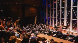 An audience watching a performance on the Pritzker stage and Millennium Park as the background.