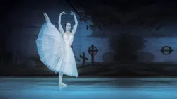 A ballerina pirouettes on a dark and gloomy stage.
