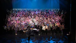 A large chorus of men singing on the Harris stage. 