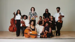 D-Composed posing on stage with their instruments.