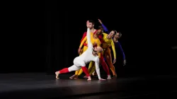 Dancers in different color bodysuits join together.
