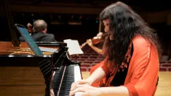 Wu Han playing the piano while other musicians play in the background