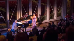 J'Nai Bridges performing in front of an audience while Craig Terry plays the piano.