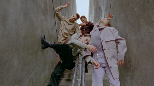 Four dancers move in a narrow space between concrete walls, limbs intertwined and braced against the surfaces