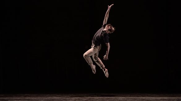 dancer leaps upward with one hand in the air