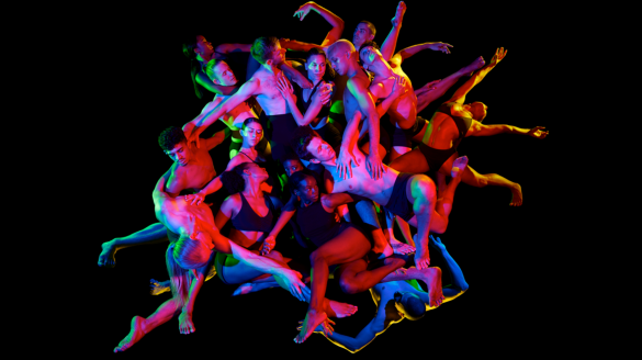 Hubbard Street Dance Chicago dancers huddle together with a black background