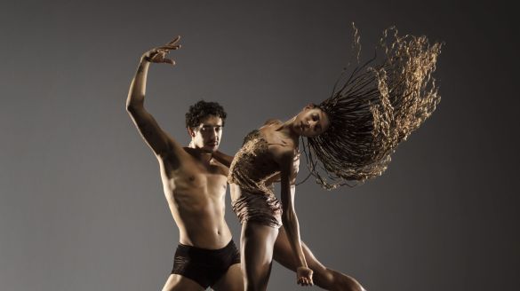 Two dancers pose against a grey backdrop